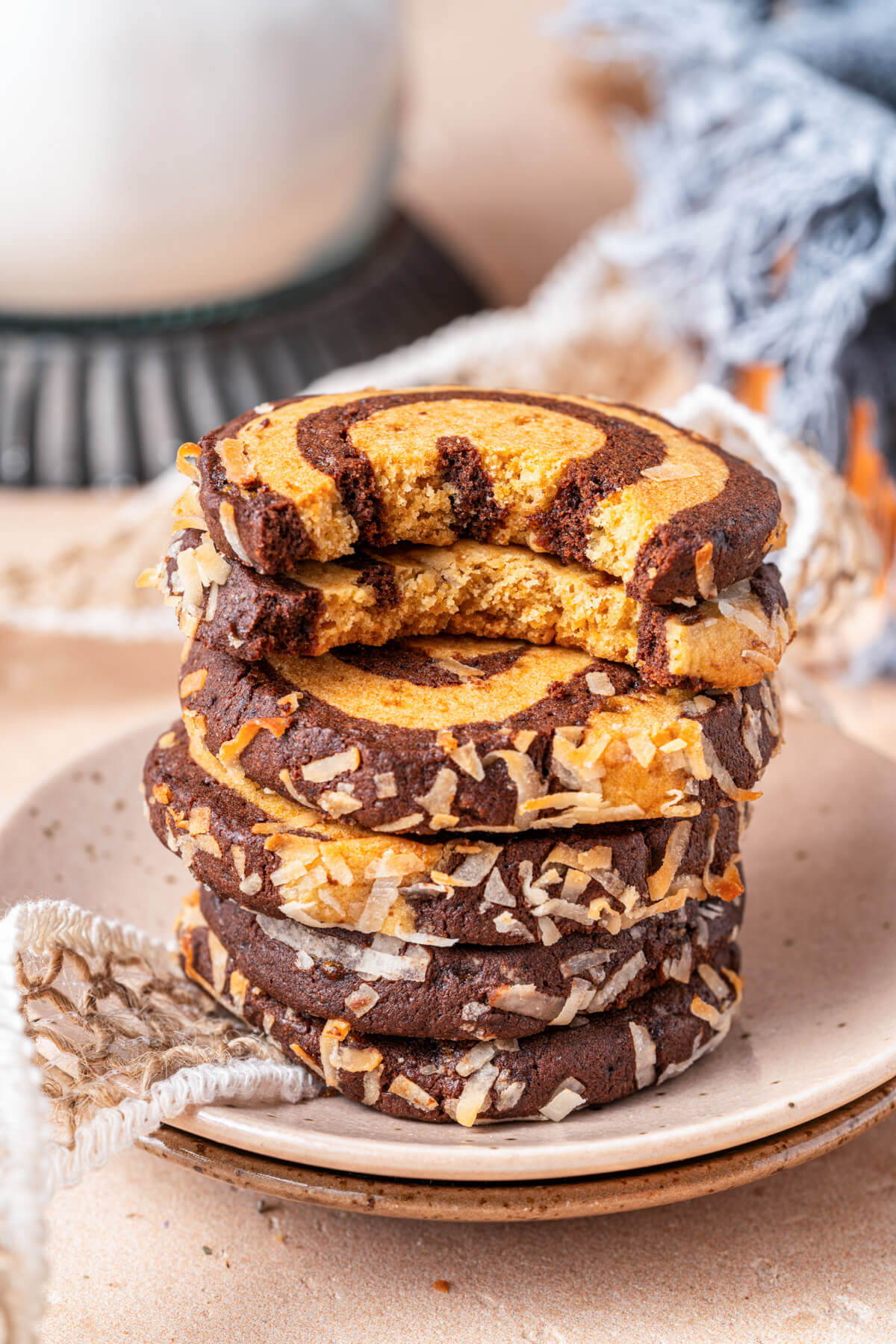 A stack of coconut coated chocolate and vanilla pinwheel cookies missing bites.
