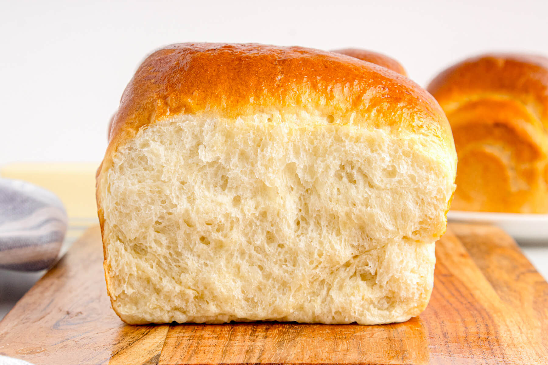A sliced loaf of pillowy soft Japanese Milk Bread on a wooden cutting board.