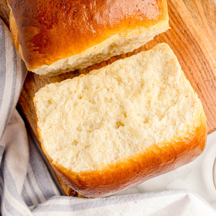 A pillowy soft slice of Japanese Milk Bread on a wooden cutting board.