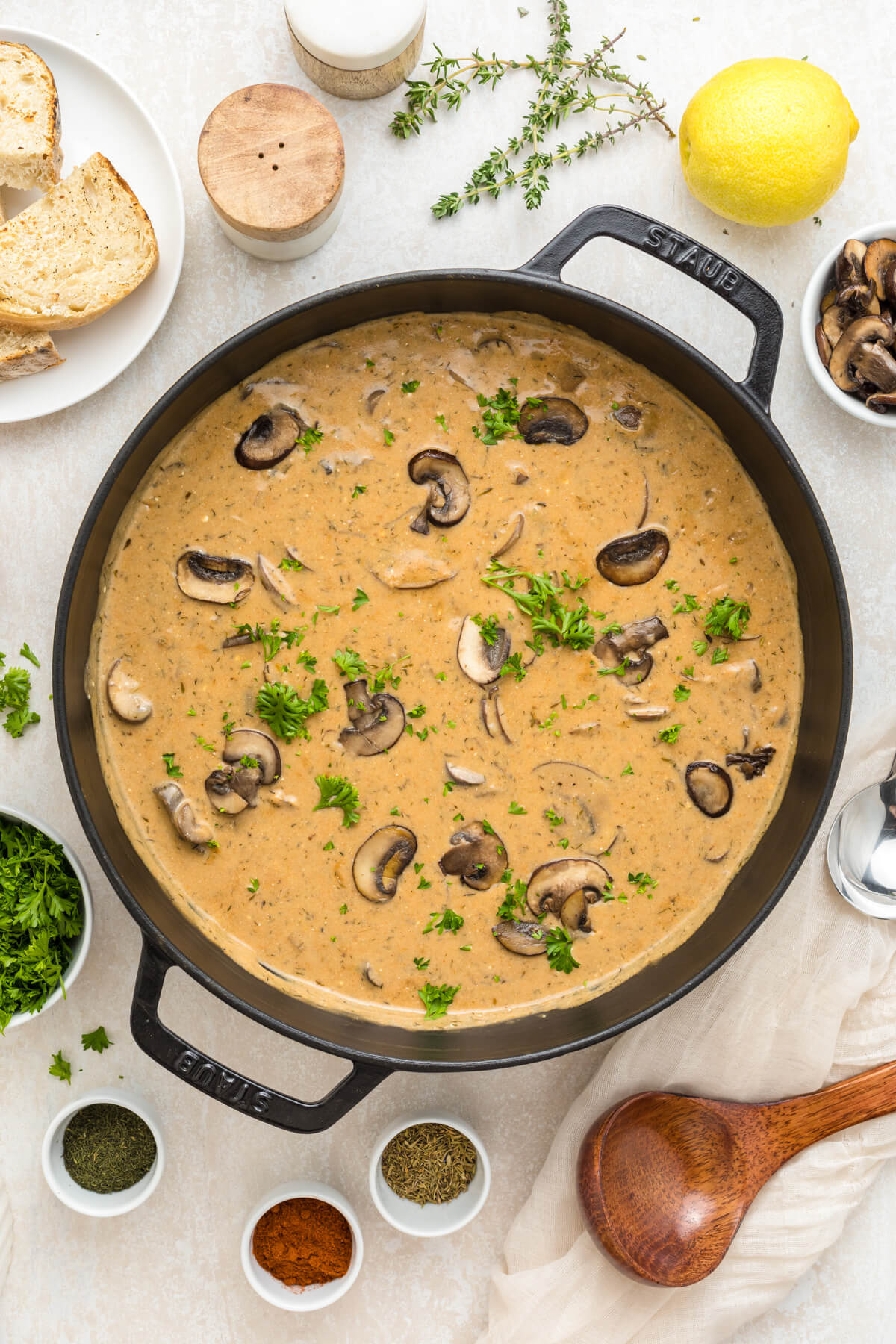 A black Dutch oven full of rich creamy Hungarian Mushroom Soup topped with vibrant green herbs.