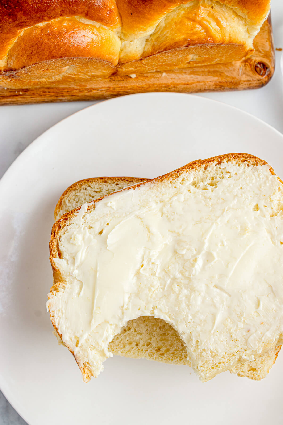 A slice of shokupan bread slathered with butter on a white plate