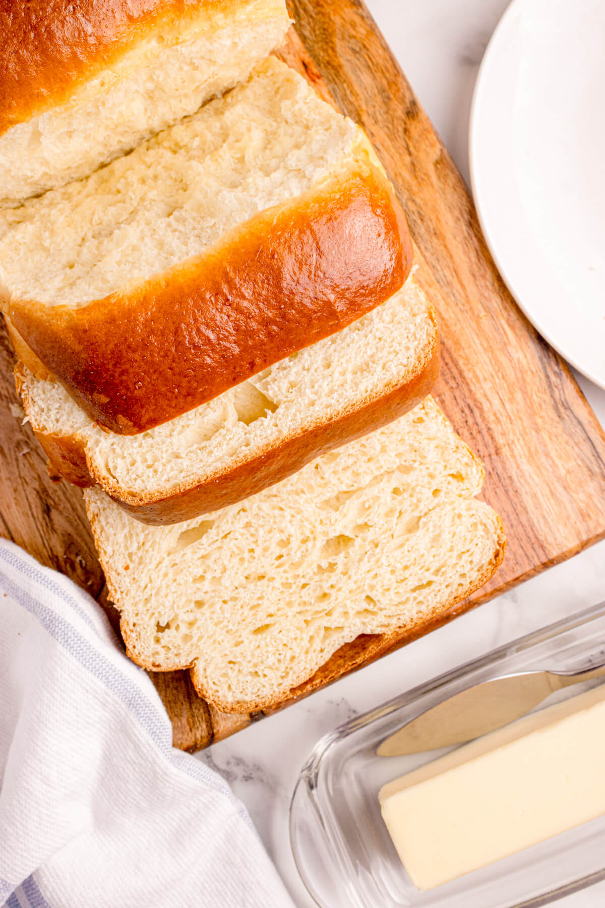 Fresh slices of shokupan bread showing the light and fluffy interior texture on a wooden cutting board.
