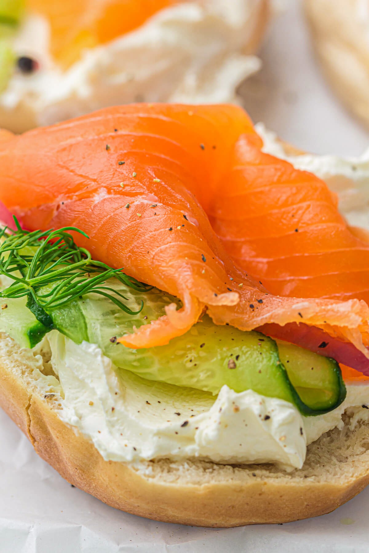 A bagel filled with thin slices of cold smoked salmon, sliced cucumbers, and cream cheese.