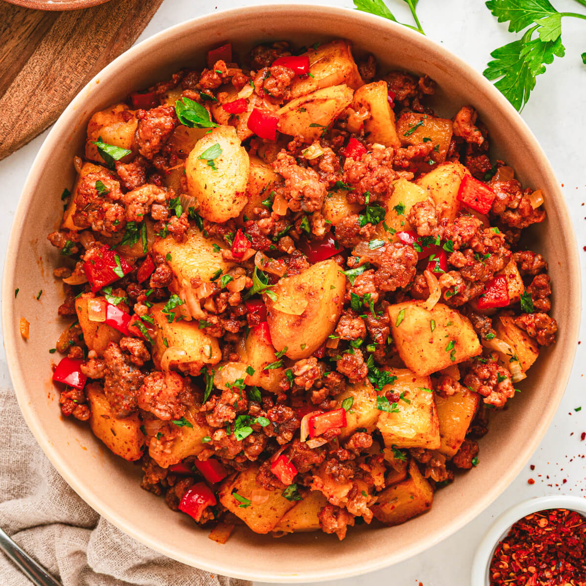 A breakfast bowl filled with vibrant papas con chorizo containing red peppers, potatoes, chorizo and cilantro as garnish.