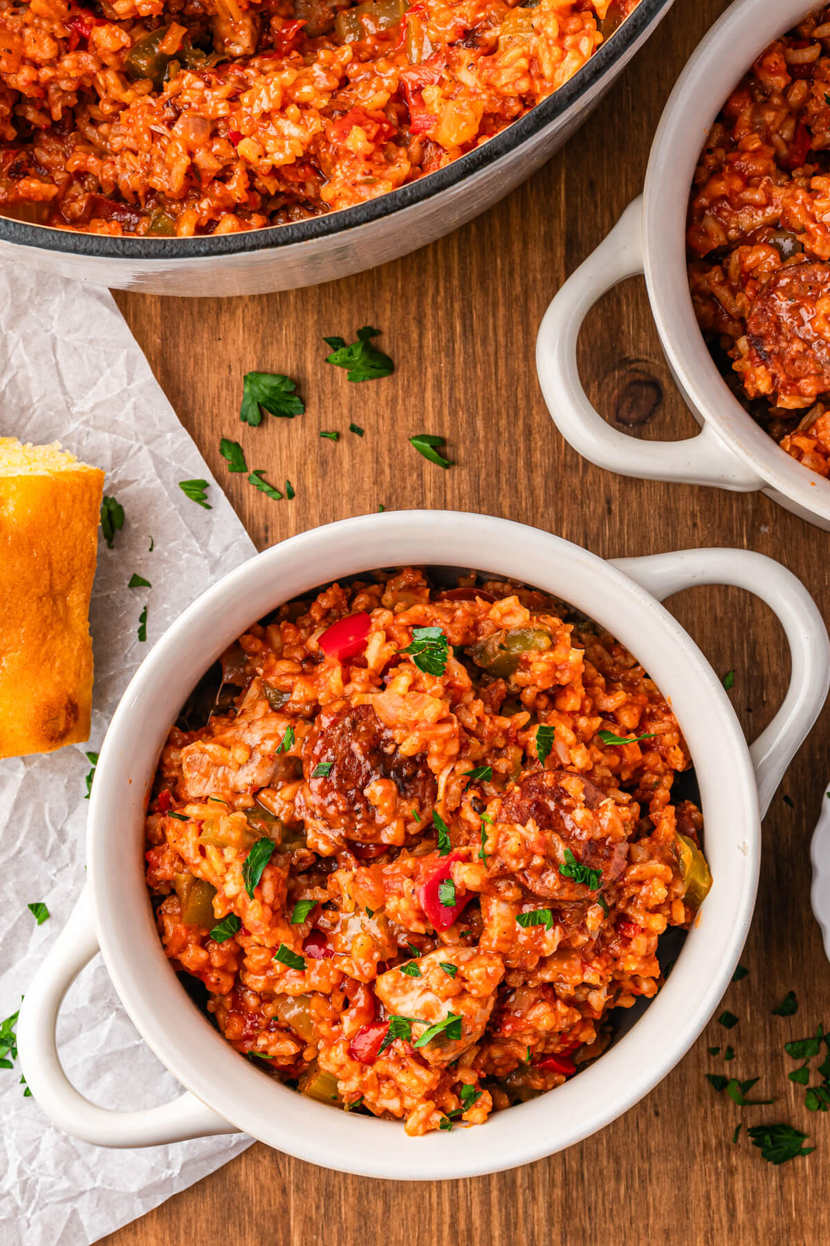 A bowl of vibrant red sausage chicken jambalaya with red and green bell peppers garnished with fresh parsley.