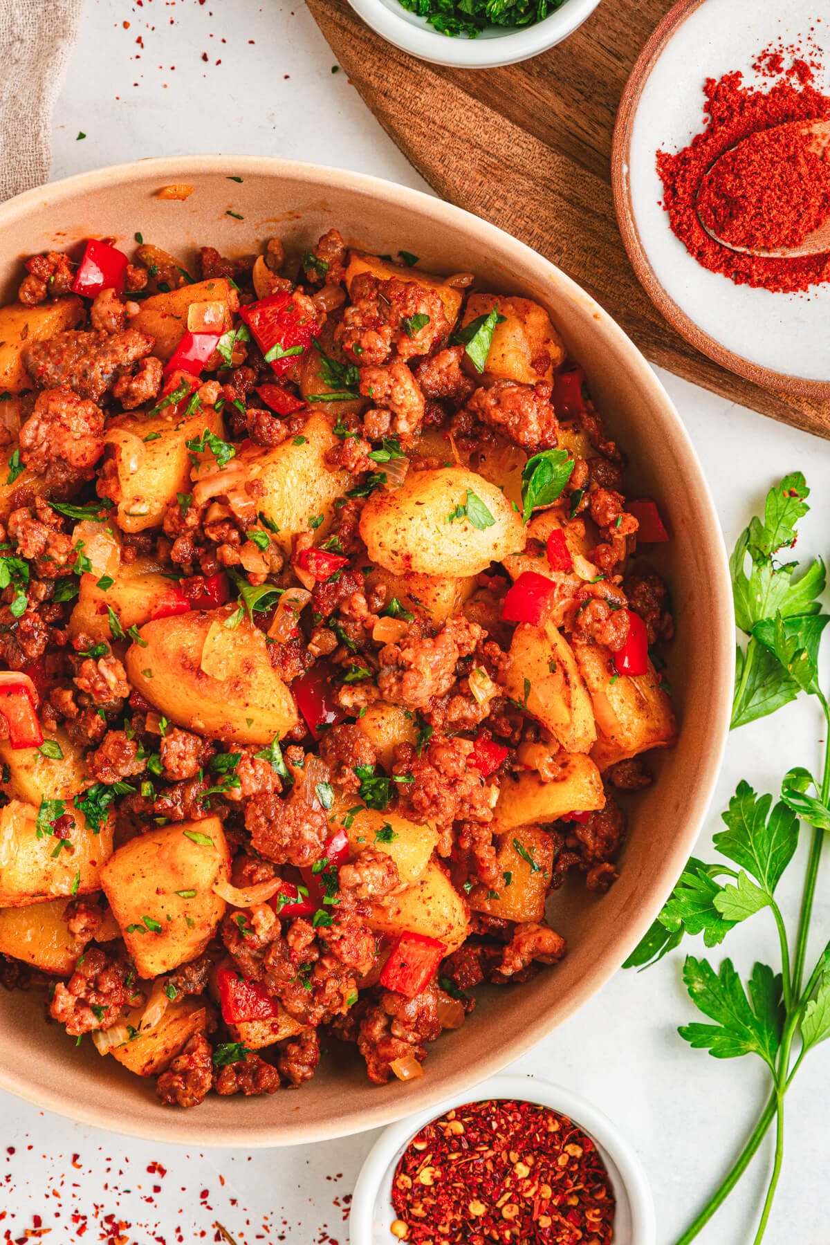 A breakfast bowl filled with vibrant papas con chorizo containing red peppers, potatoes, chorizo and cilantro as garnish.