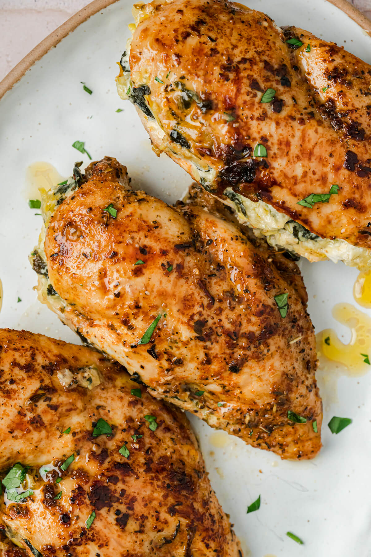 Three golden seared chicken breasts stuffed with creamy spinach and artichoke stuffing.
