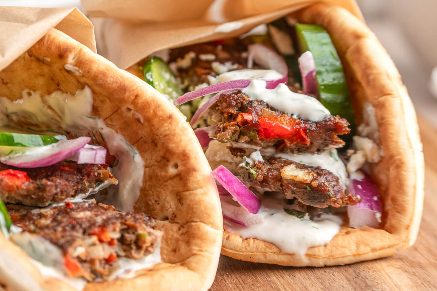 Two pita wraps filled with sheet pan kebabs, vegetables, and yogurt tahini sauce.