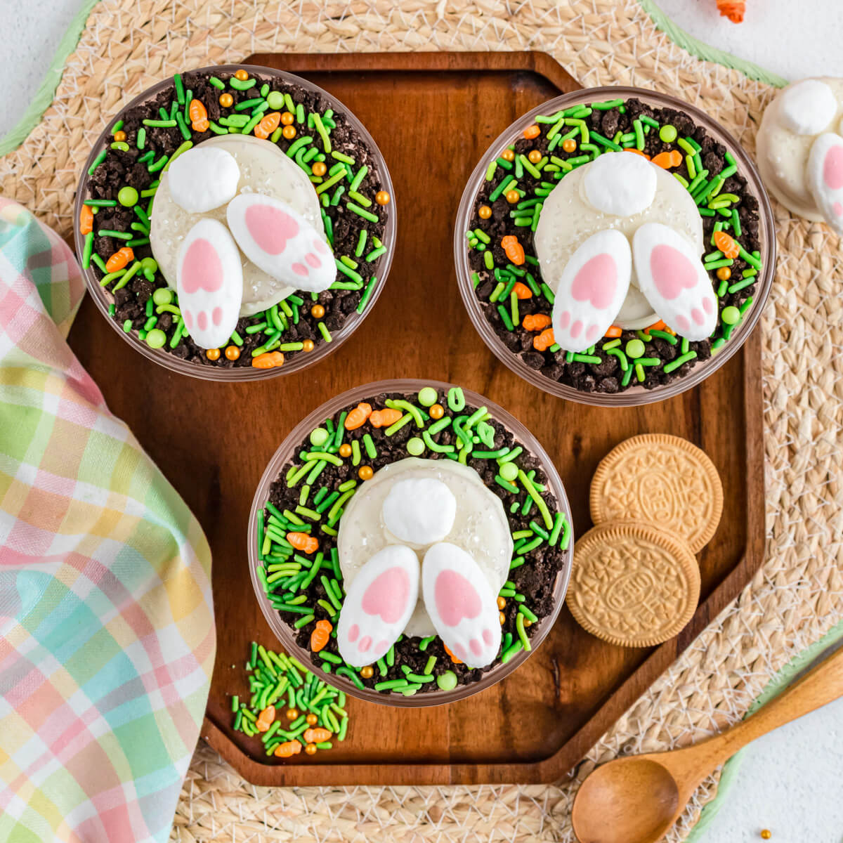 A trio of Easter Trifles topped with adorable bunny butt cookies on a dessert table.