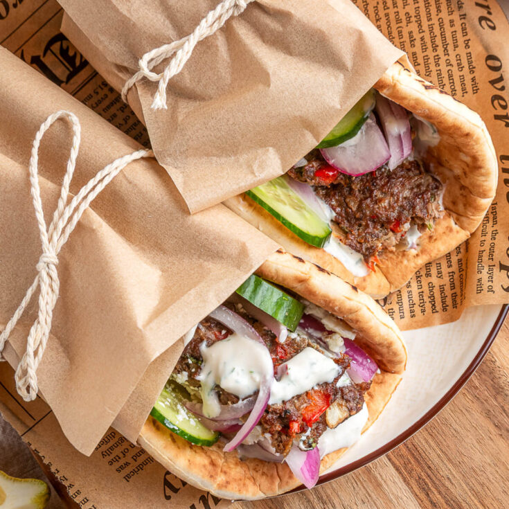 Two pita wraps filled with sheet pan kebabs, vegetables, and yogurt tahini sauce.