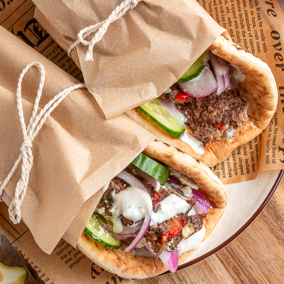 Two pita wraps filled with sheet pan kebabs, vegetables, and yogurt tahini sauce.