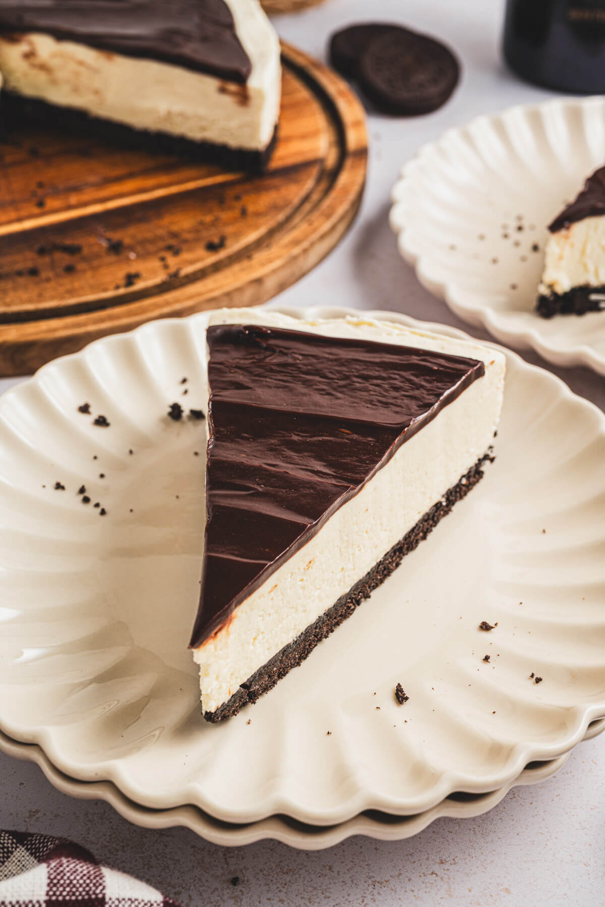 A slice of Bailey's Cheesecake topped with chocolate ganache on a dessert plate.