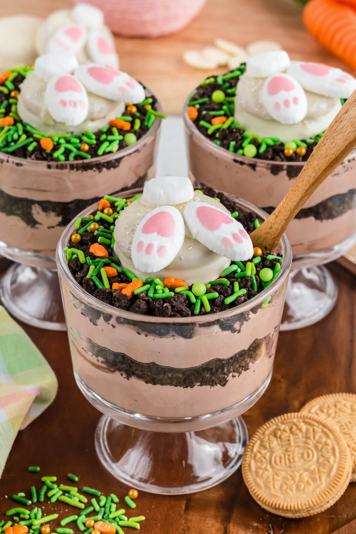 A trio of Easter Trifles topped with adorable bunny butt cookies on a dessert table.