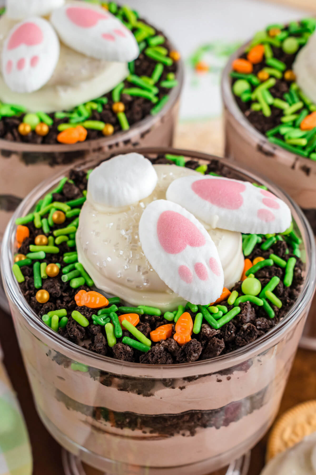 A trio of Easter Trifles topped with adorable bunny butt cookies on a dessert table.