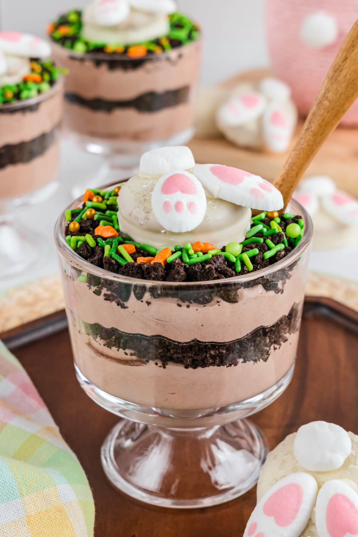 An individual Easter trifle featuring layers of cookie crumb dirt and chocolate whipped cream topped with a bunny butt cookie.