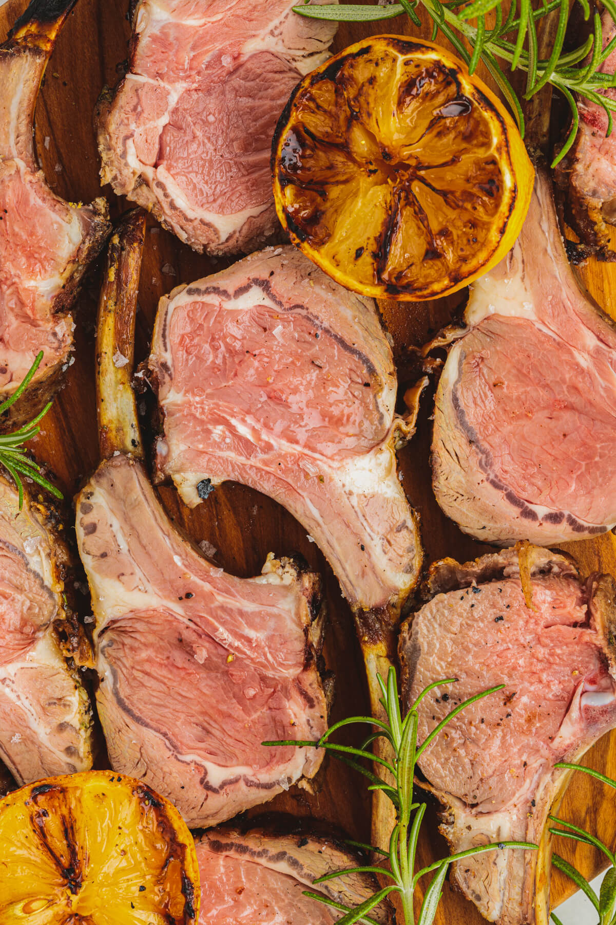 Several pink slices of lamb on a wooden serving board.