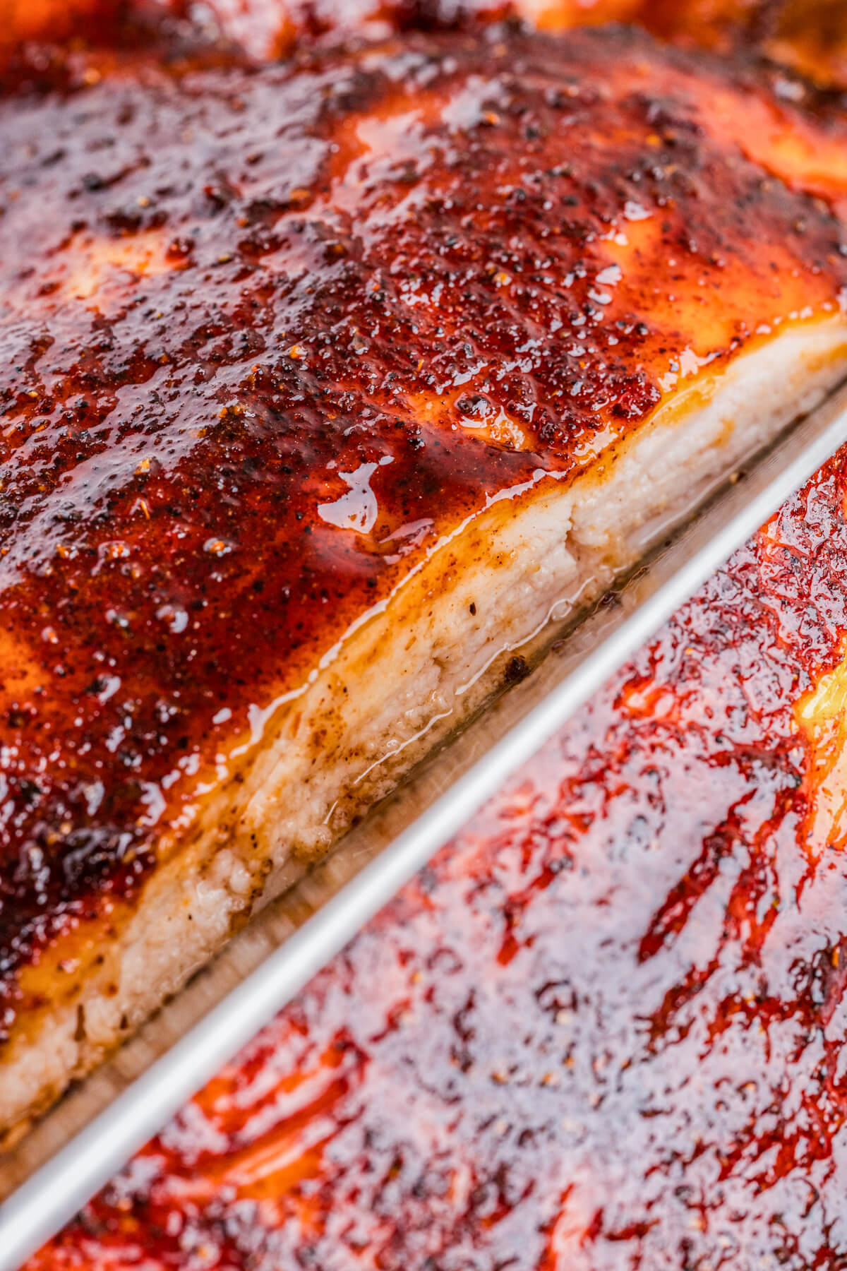 A knife slicing into a juicy smoked bbq chicken breast.