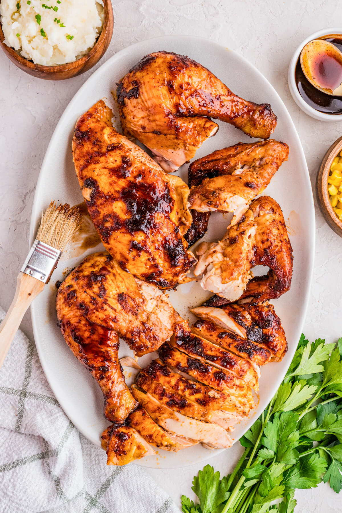 A platter of smoked bbq chicken pieces surrounded by dinner side dishes.