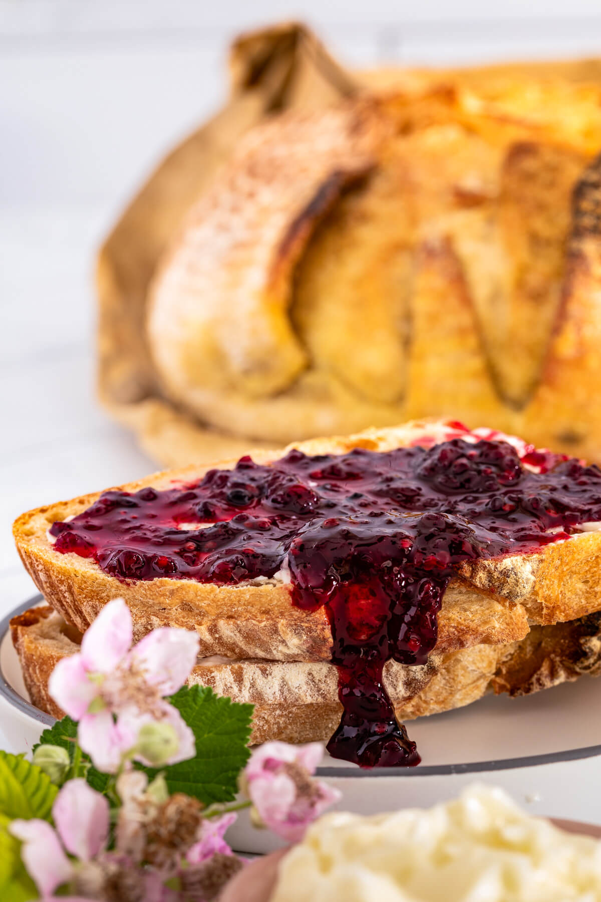 Blackberry jam drips over the edge of a buttered sourdough toast stack.