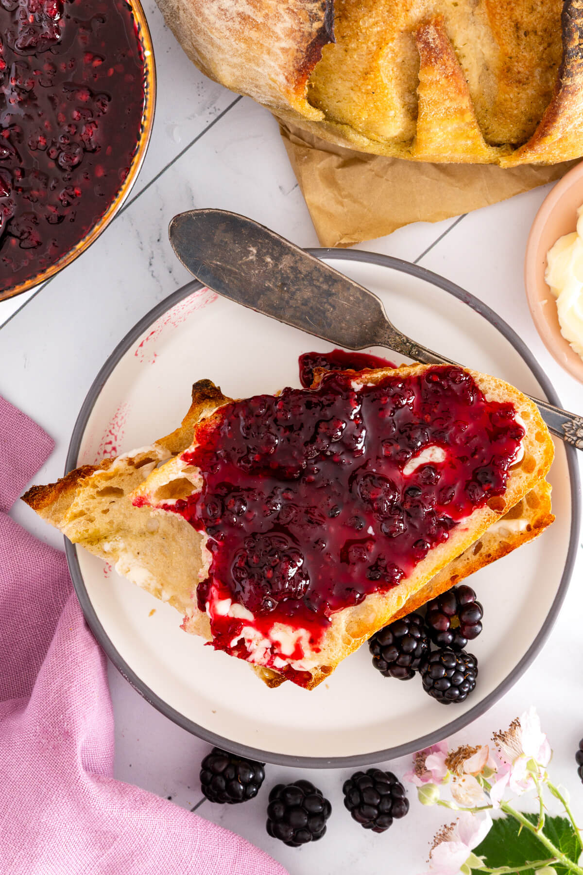 A plate holding sourdough toast spread with blackberry jam. 