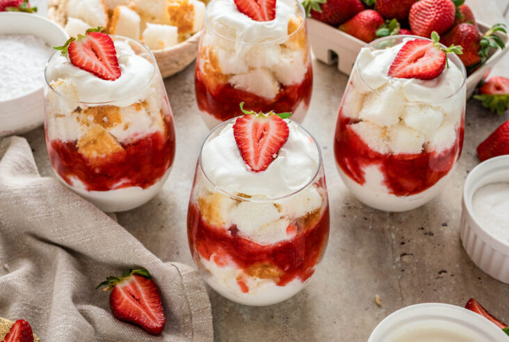 A group of strawberry trifles in stemless wine glasses showing the layers.