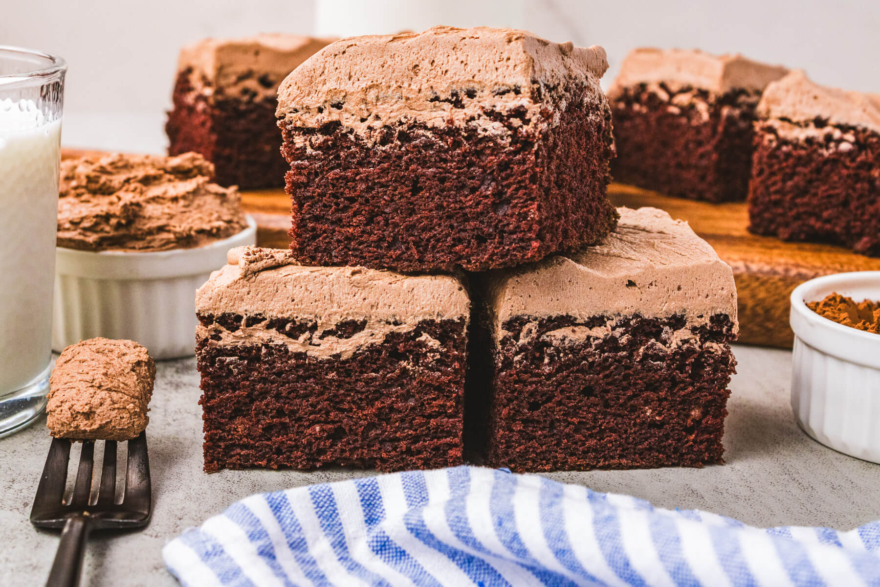 Three squares of chocolate wacky cake stacked into a pyramid  on a table.