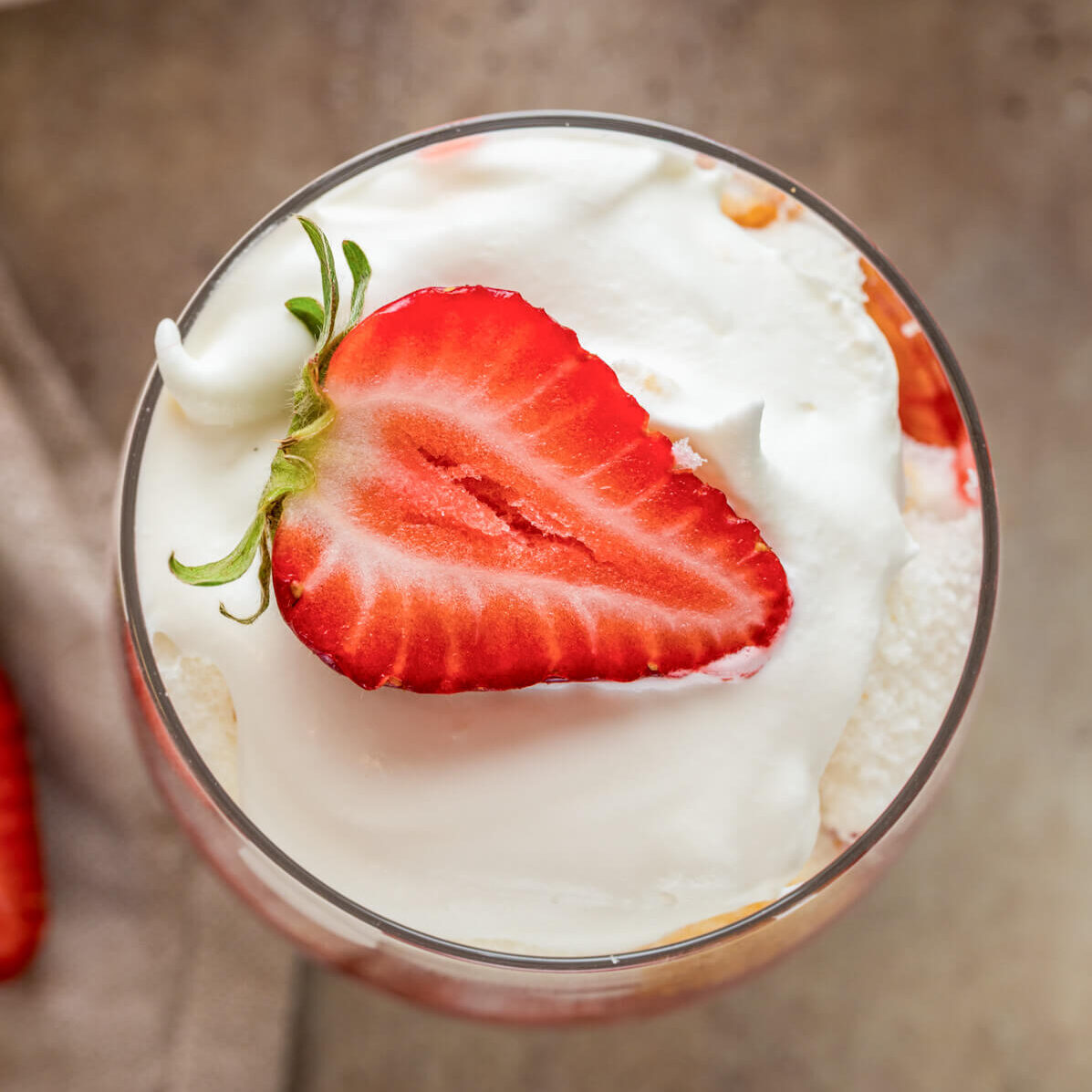 One dreamy strawberry trifle topped with whipped cream and a sliced strawberry.