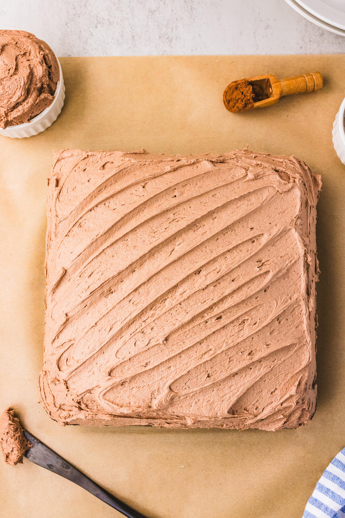 A whole frosted chocolate wacky cake on a wooden cutting board.