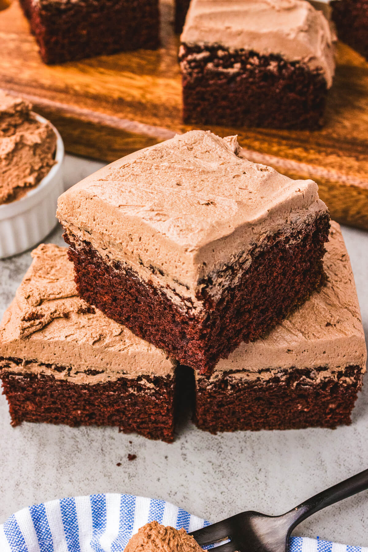 Three squares of chocolate wacky cake stacked into a pyramid on a table.