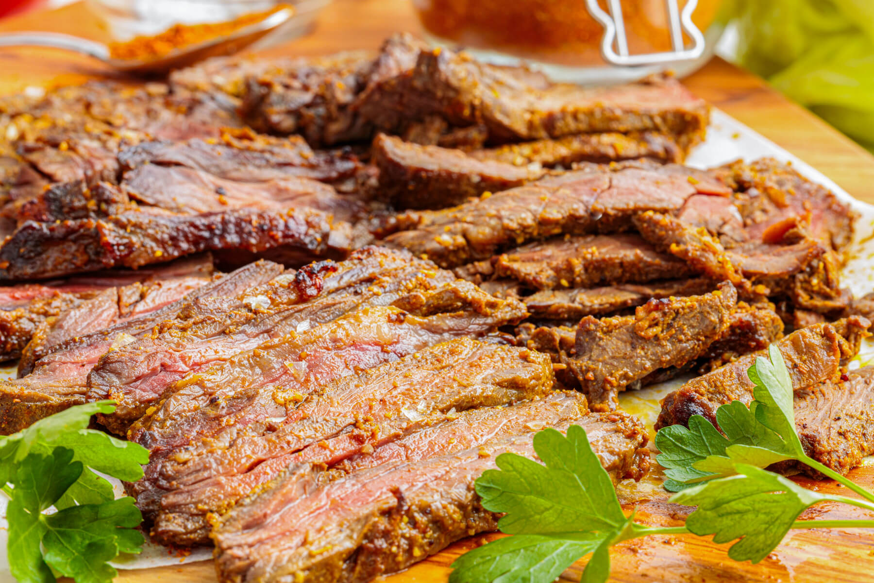 Slices of juicy looking marinated and broiled beef shawarma on a cutting board.