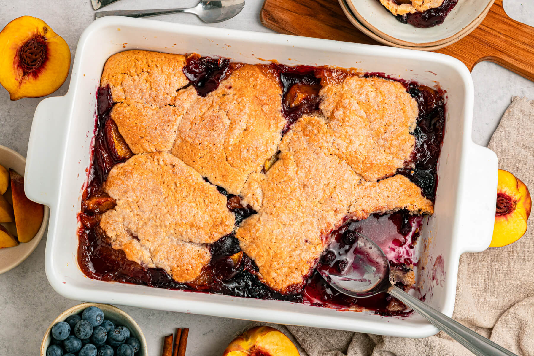 A white baking dish of Peach Blueberry cobbler.