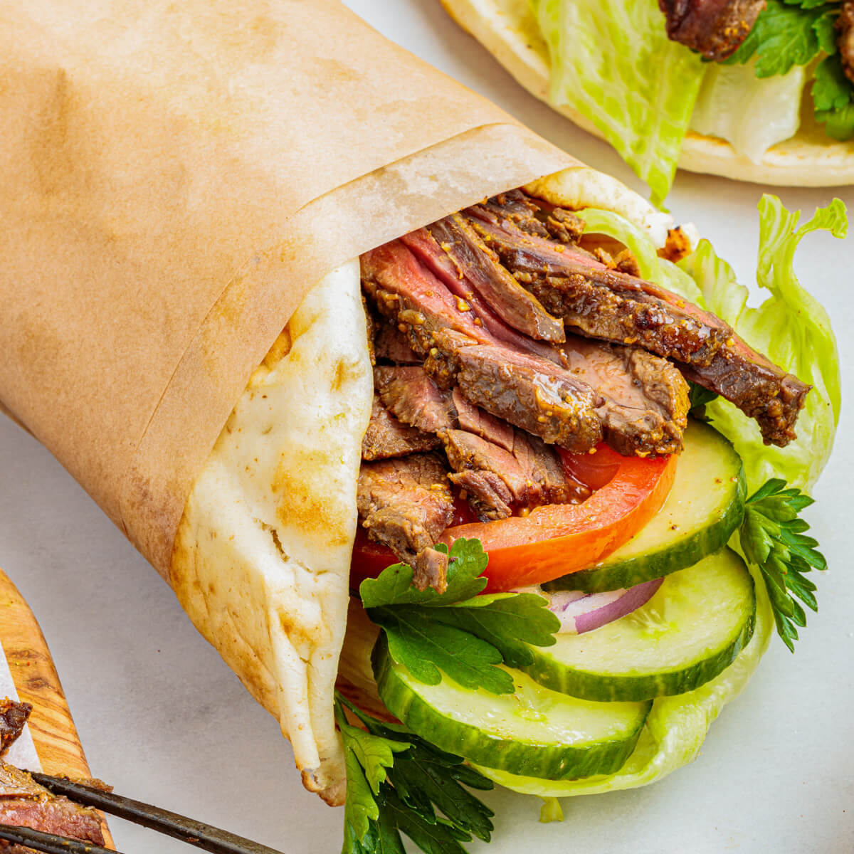 Slices of perfectly seared homemade beef shawarma in a pita wrap with vegetables.