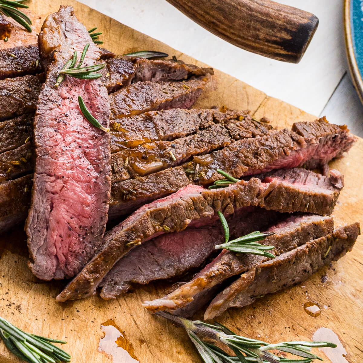 Strips of perfectly seared cast iron skillet steak on a cutting board.