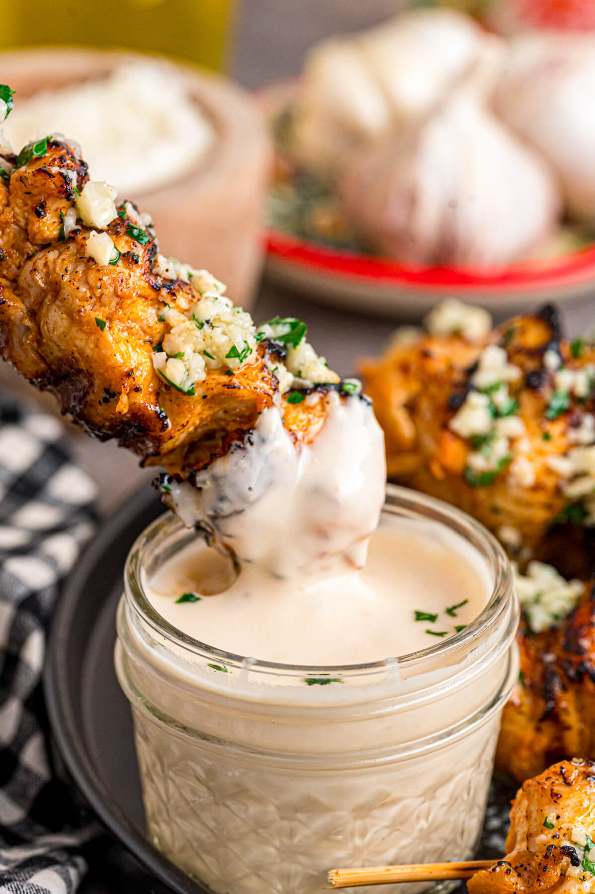 A Garlic parmesan chicken skewer being dipped into a creamy dipping sauce.