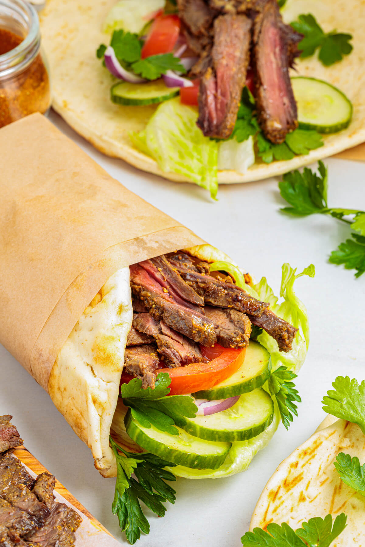 Slices of perfectly seared homemade beef shawarma in a pita wrap with vegetables.
