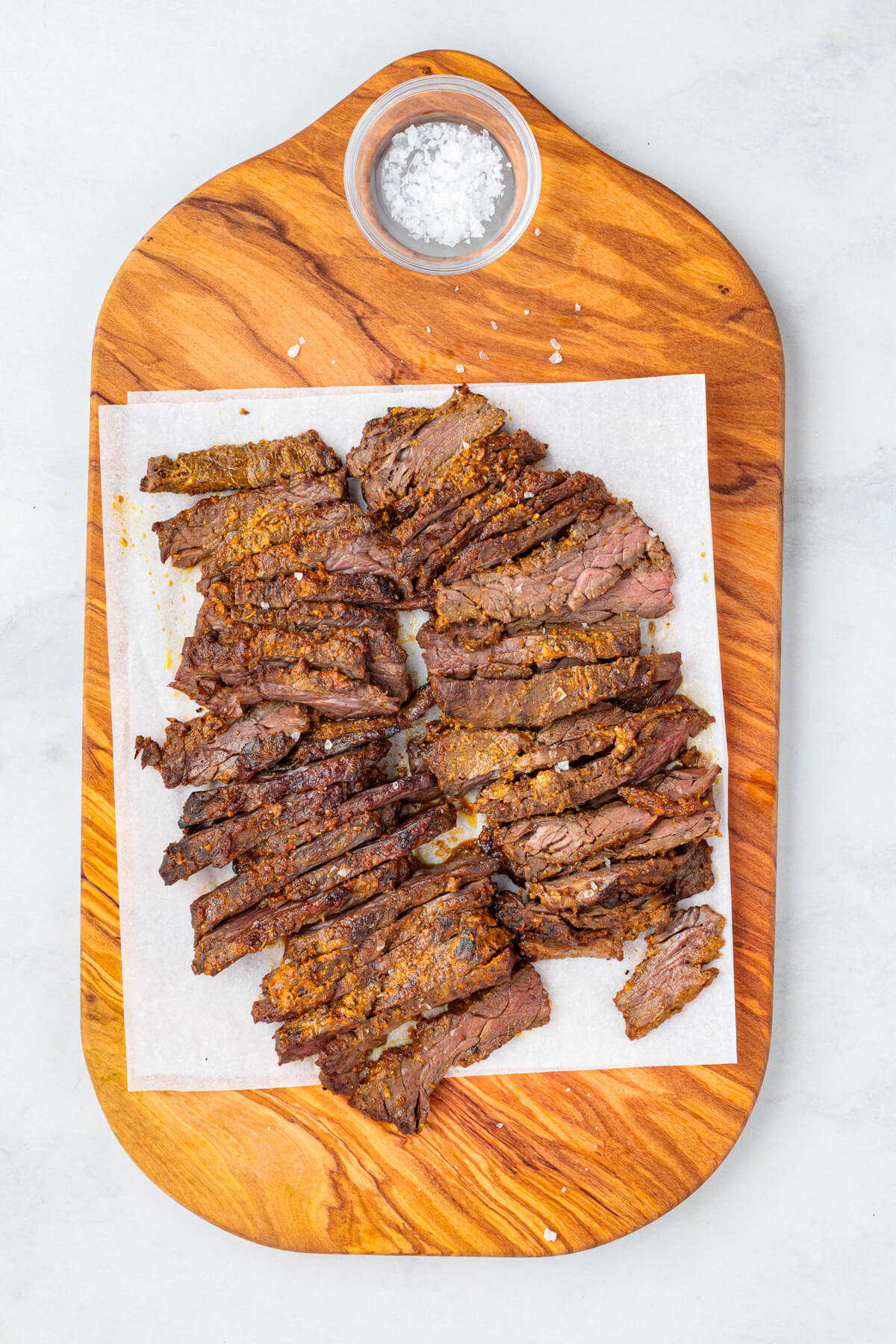 Slices of juicy looking marinated and broiled beef shawarma on a cutting board.