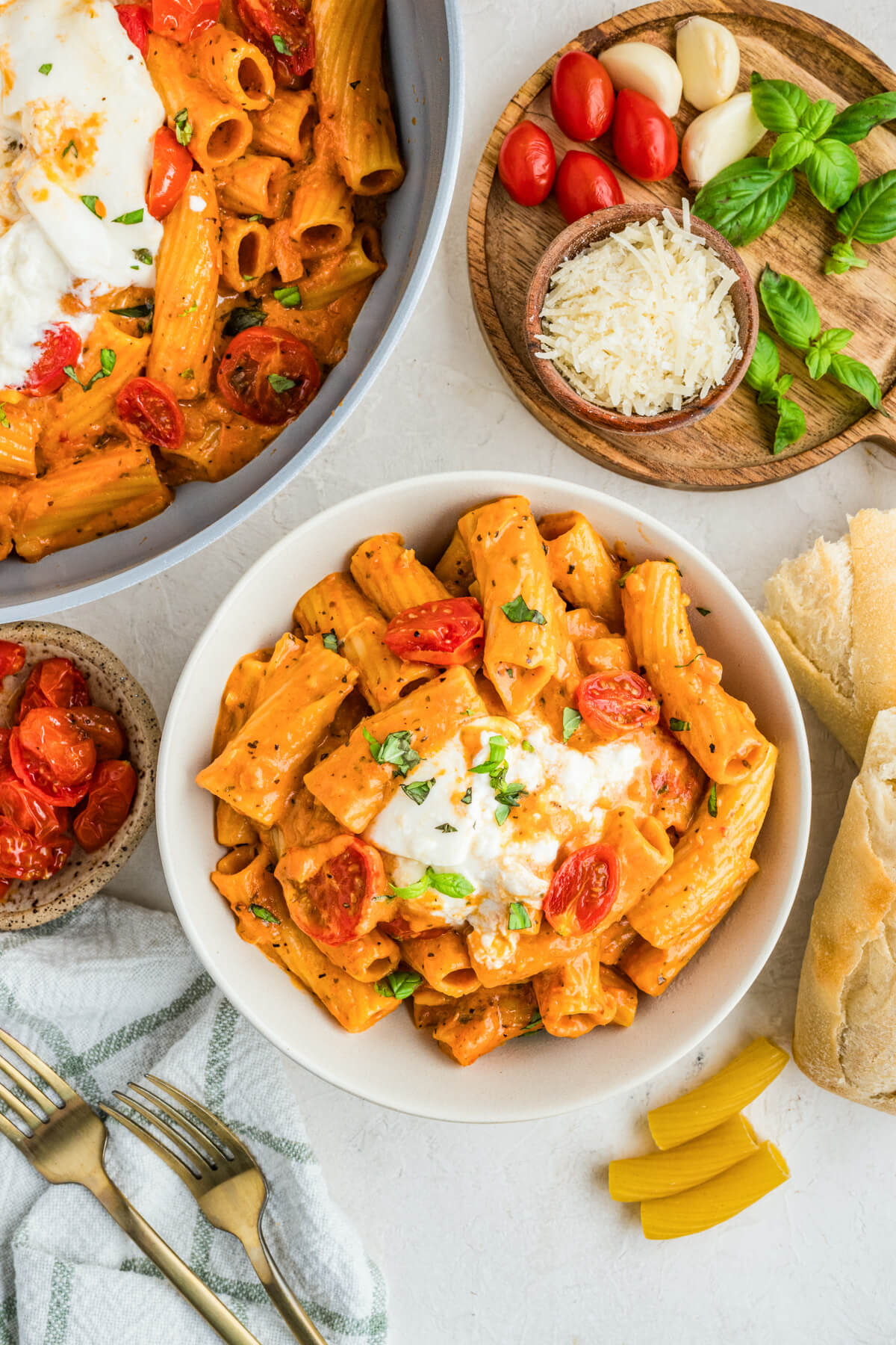 A table scene featuring a pot and pasta bowl full of burrata topped pasta.