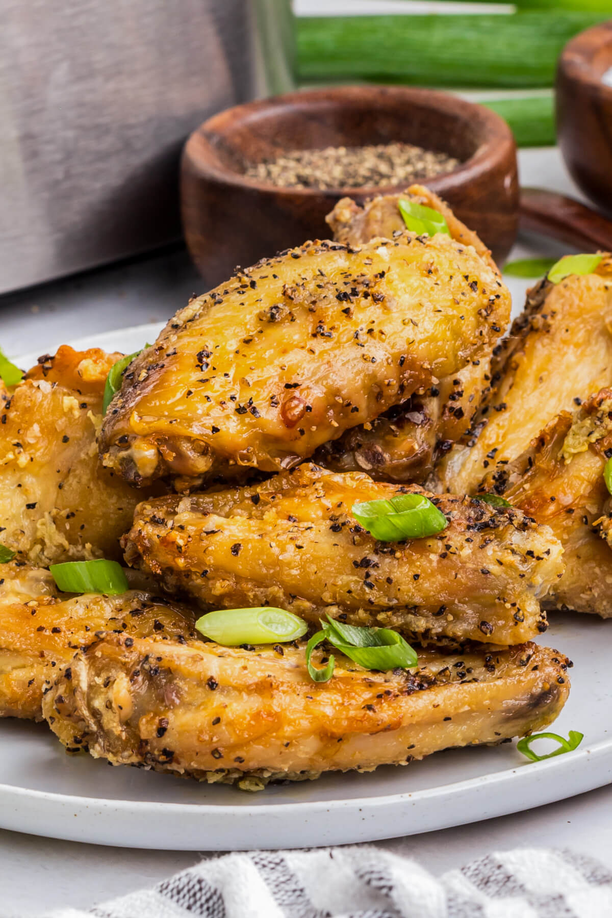 A plate full of golden brown crispy Salt and Pepper Wings garnished with sliced green onions.