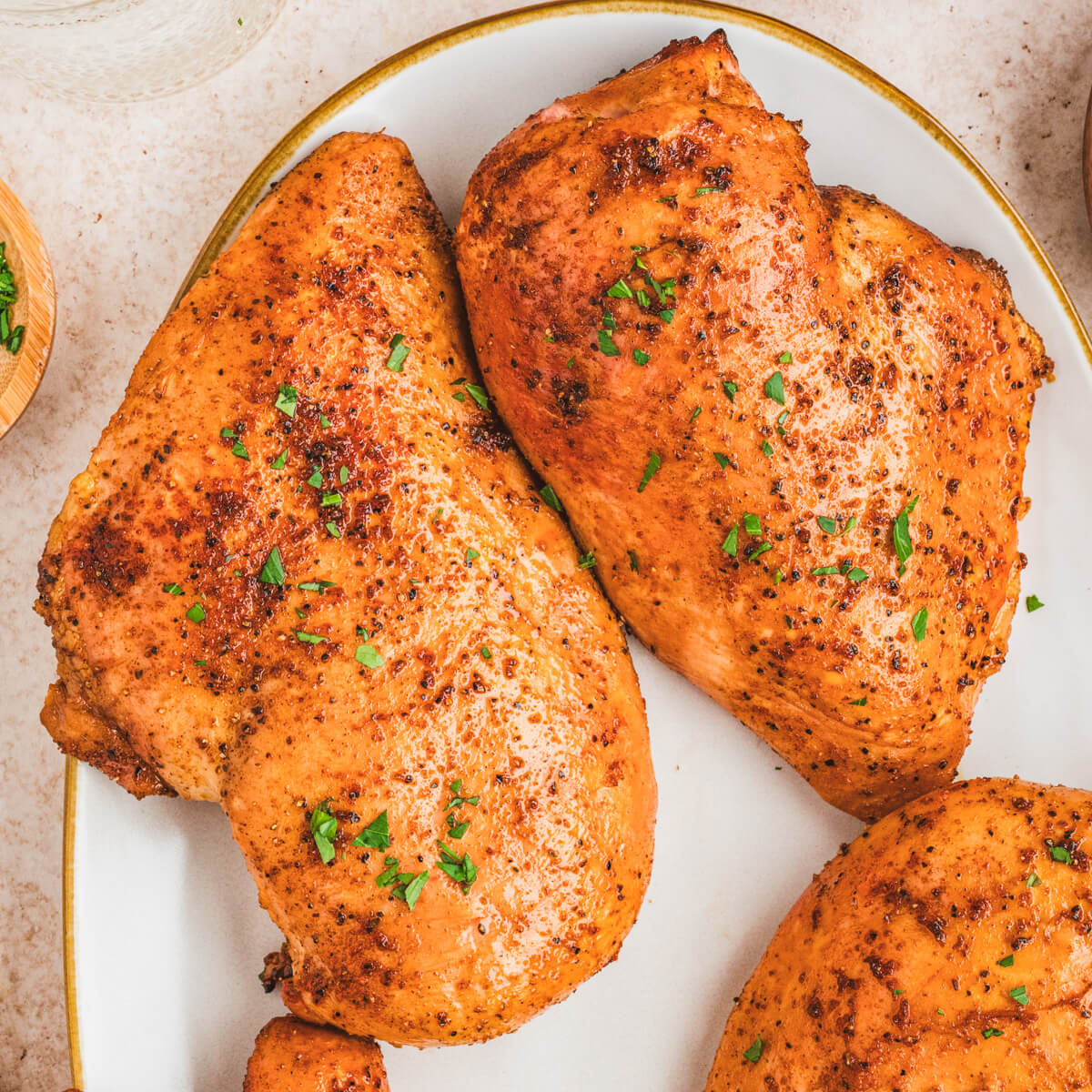 Several juicy smoked chicken breasts on a plate. 