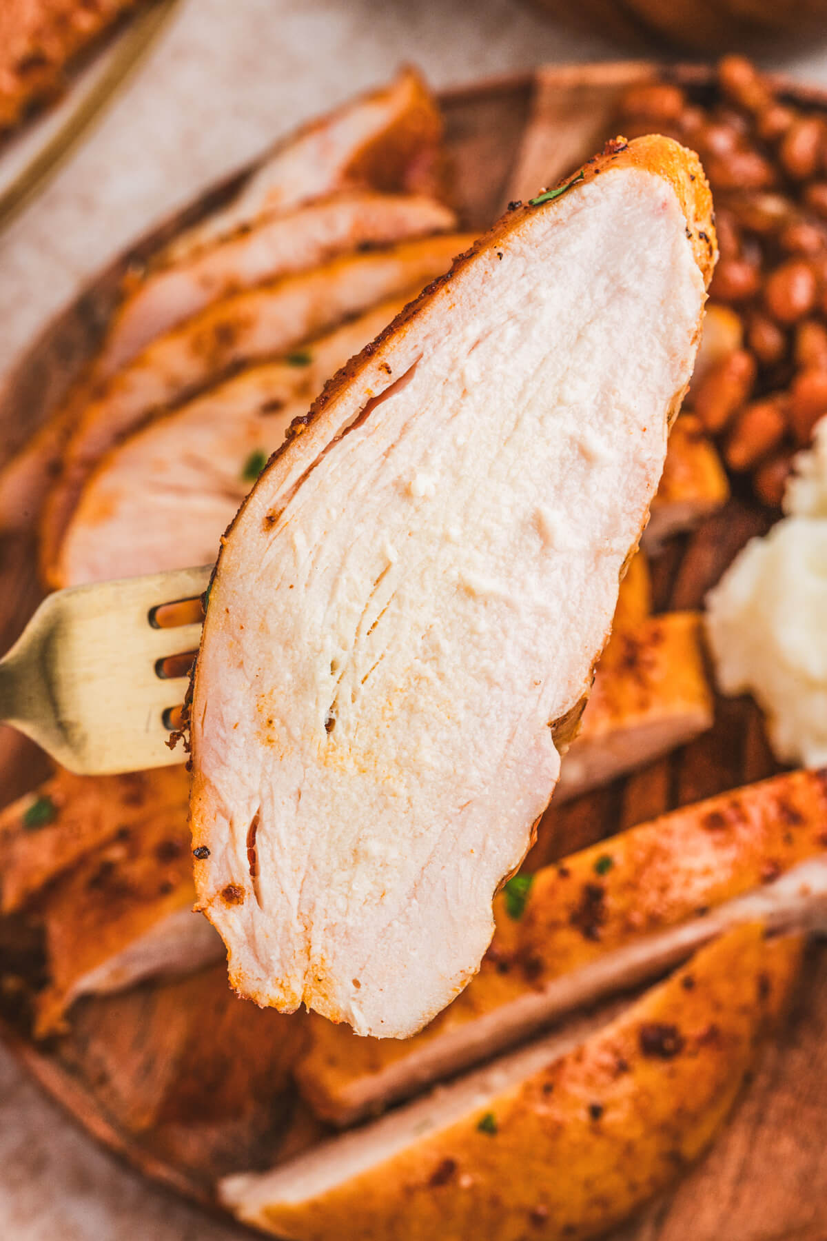 A juicy slice of smoked chicken breast on a fork.