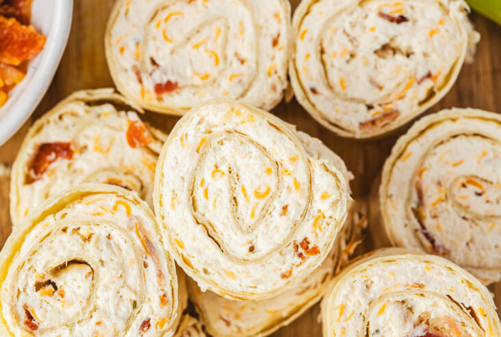 A pile of tortilla pinwheels filled with cream cheese mixture containing bacon, cheddar cheese, and shredded chicken.