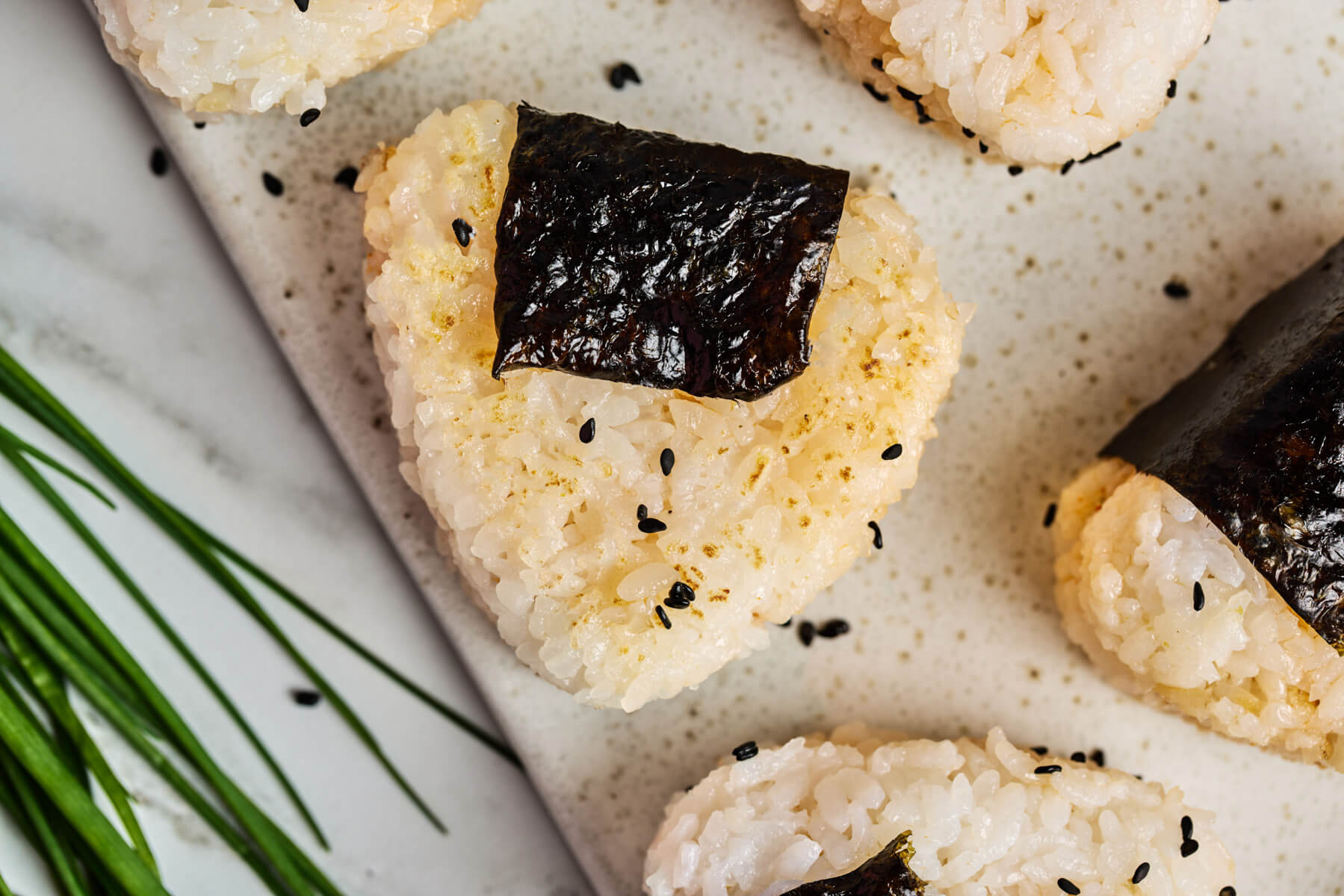One Japanese Onigiri wrapped in nori and garnished with black sesame seeds.