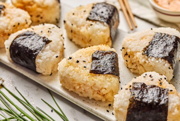 A tray of seasoned Japanese Onigiri wrapped in nori and garnished with black sesame seeds.