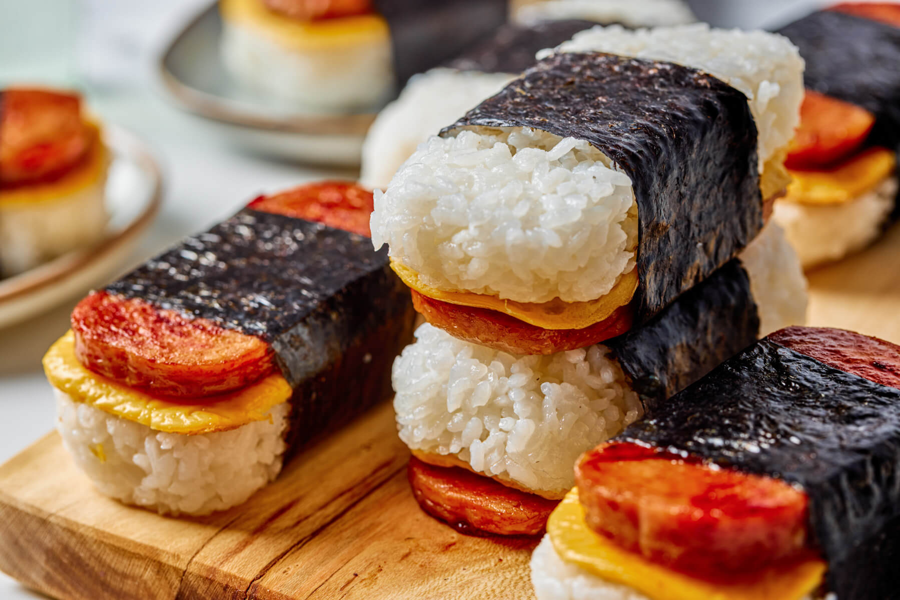 Several layered Spam and Egg Musubi wrapped in nori strips on a wooden serving board.