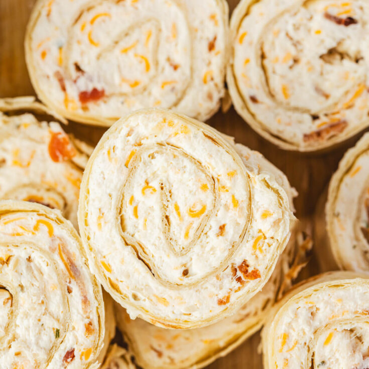 A pile of tortilla pinwheels filled with cream cheese mixture containing bacon, cheddar cheese, and shredded chicken.