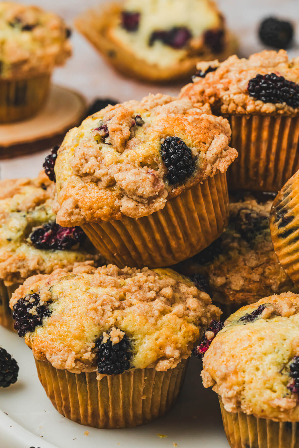 A pile of golden baked blackberry muffins topped with crunchy streusel.
