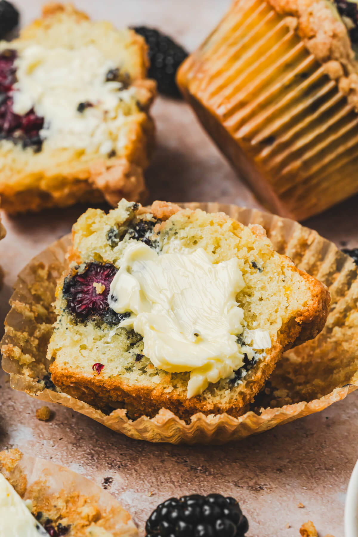 A golden baked blackberry muffin sliced open and spread with a pat of butter.