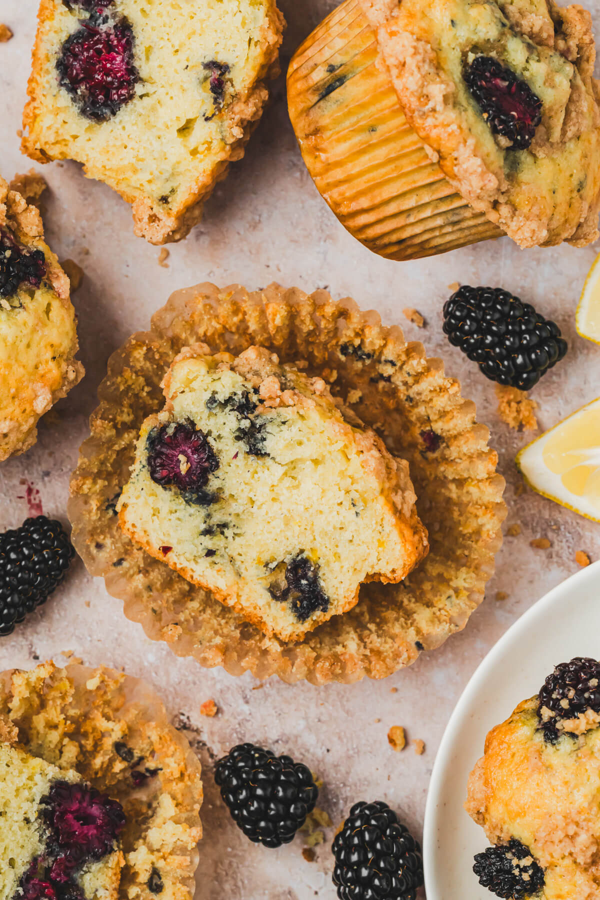 A group of golden baked blackberry muffins with the middle one sliced open.