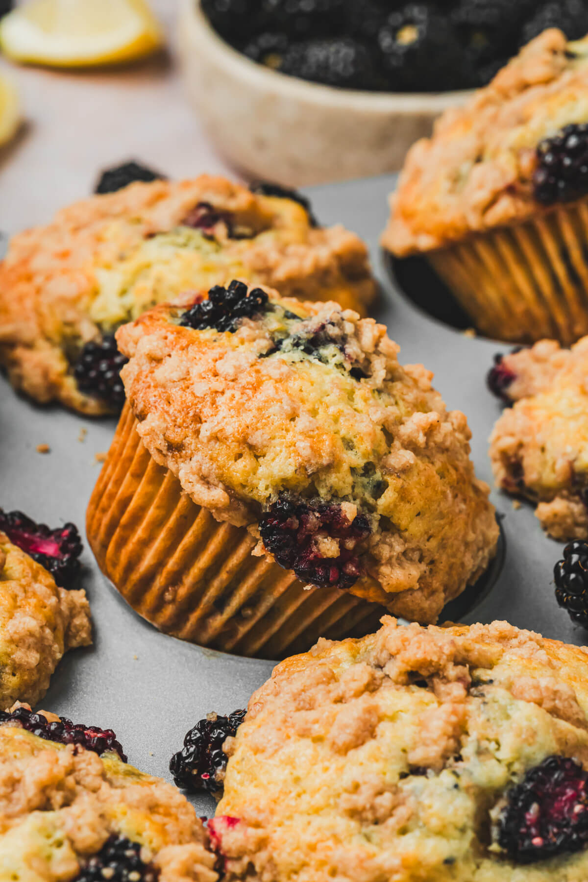 Golden baked Blackberry muffins in a muffin tin.