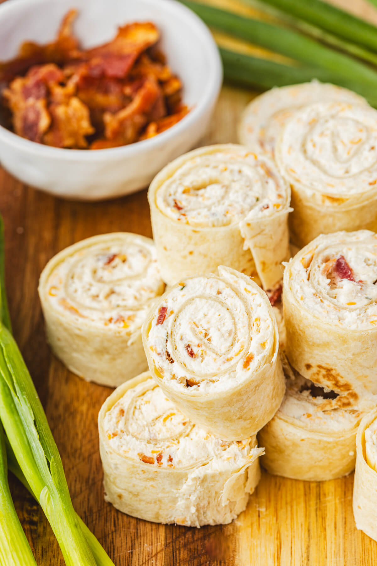 A pile of tortilla pinwheels filled with cream cheese mixture containing bacon, cheddar cheese, and shredded chicken.